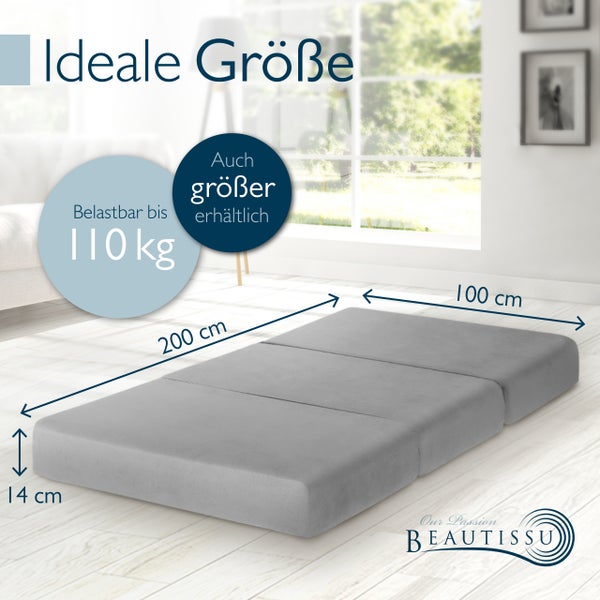 Graue faltbare Gästematratze Beautissu mit Maßen 200 mal 100 mal 14 Zentimeter und einer Belastbarkeit bis 110 Kilogramm in einem Wohnraum.