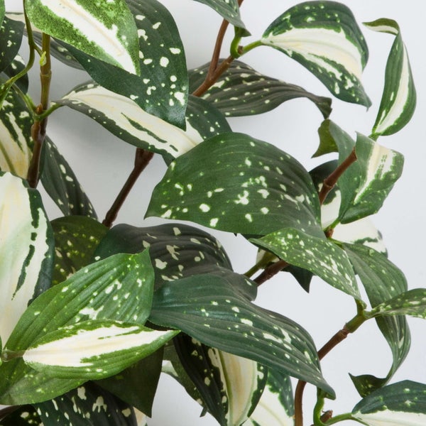 Künstliche Pflanze mit grün-weiß gemusterten Blättern und braunem Stiel.