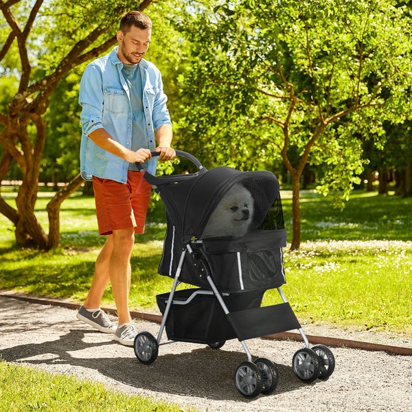Mann schiebt einen schwarzen Tierkinderwagen mit einem Hund im Park.