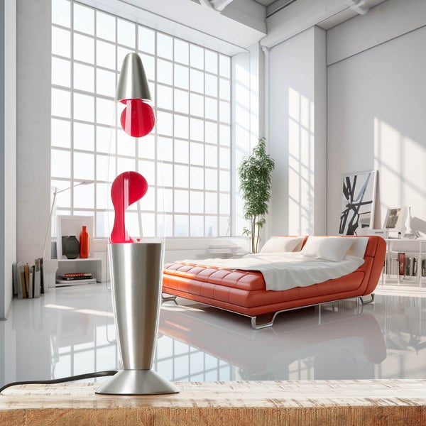 Rote Lavalampe auf einem Holztisch in einem hellen Wohnraum mit Bett und Fenster