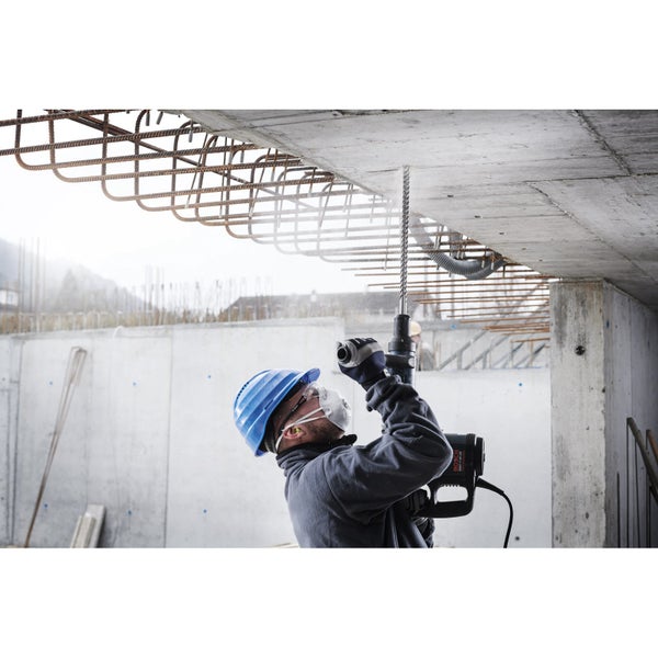 Ein Bauarbeiter bohrt mit einer Bohrmaschine in eine Betondecke.