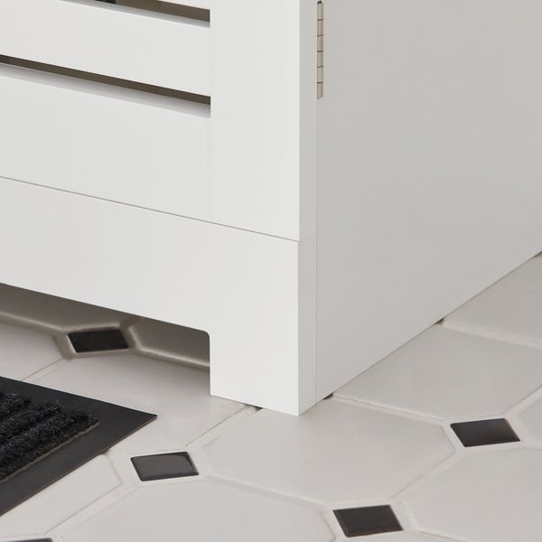 Detailansicht eines weißen Badezimmerschranks auf Fliesenboden.