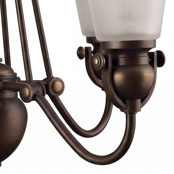 Detailansicht eines klassischen Kronleuchters mit bronzefarbenen Metallarmen und gerippten Glasschirmen aus Mattglas.