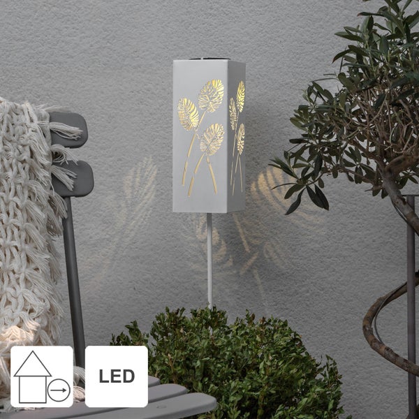 Dekorative LED-Gartenleuchte mit Pflanzenmuster neben Sitzgelegenheit und Bepflanzung