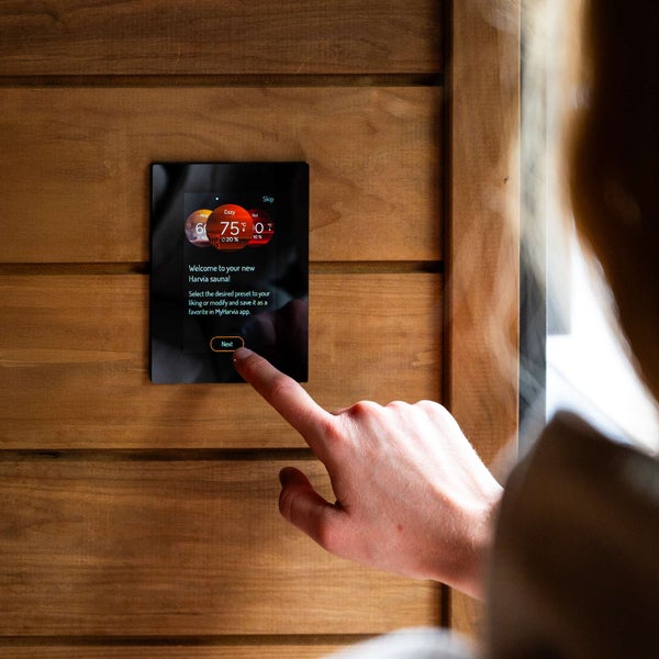 Digitale Saunasteuerung Harvia Xenio mit Touchscreen an einer Holzsaunawand montiert zur Einstellung von Temperatur und Feuchtigkeit.