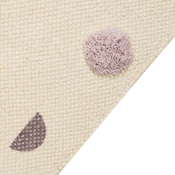 Nahaufnahme eines gewebten Teppichs in Beige mit einem flauschigen lila Punkt und einer dunkelgrauen halbkreisförmigen Struktur.