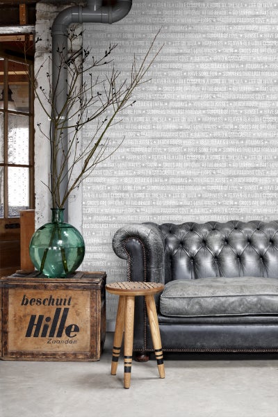 Dekoratives Wohnambiente mit Sofa, Hocker, Vase und Holzkiste