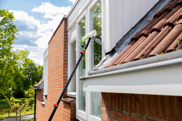 Fensterreinigung mit Teleskopstiel an einem Backsteingebäude