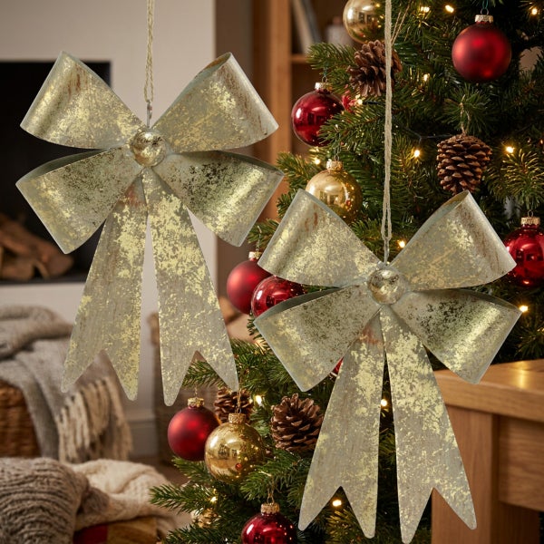 Zwei hängende Weihnachtsbaumschleifen aus Metall mit strukturierter Oberfläche in Antikoptik zur Weihnachtsdekoration.