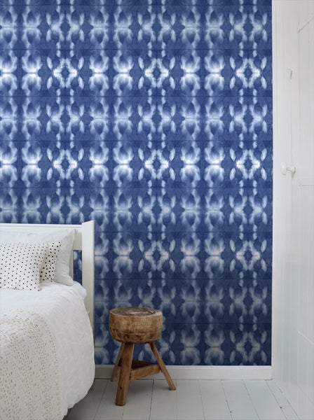 Schlafzimmer mit gemusterter Tapete und Holzhocker