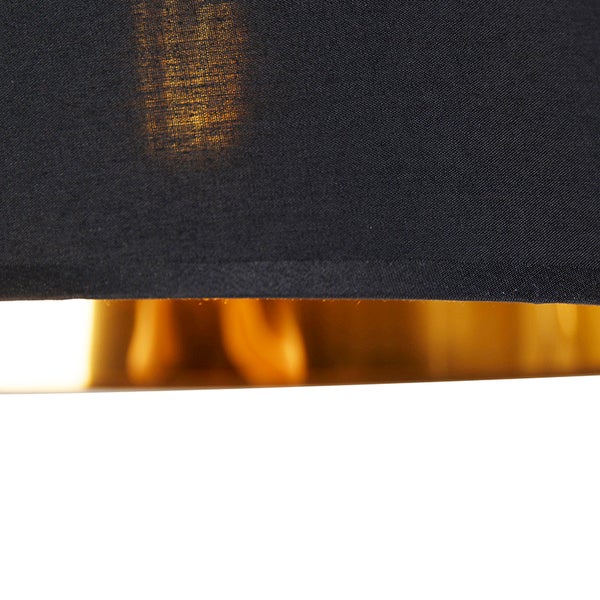 Nahaufnahme einer schwarzen Lampenschirmunterseite mit goldfarbenem Interieur