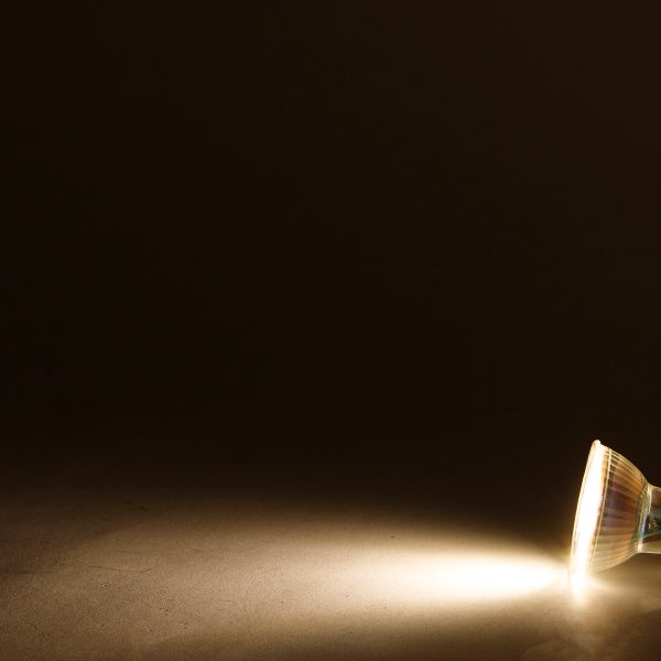 Eingeschaltetes LED Leuchtmittel strahlt einen gerichteten Lichtkegel auf eine ebene Fläche ab.