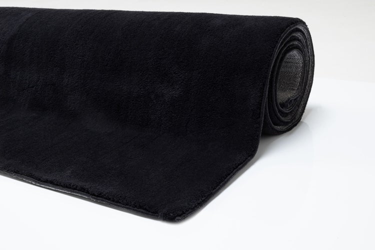 Gerollte, weiche Badmatte in Schwarz.