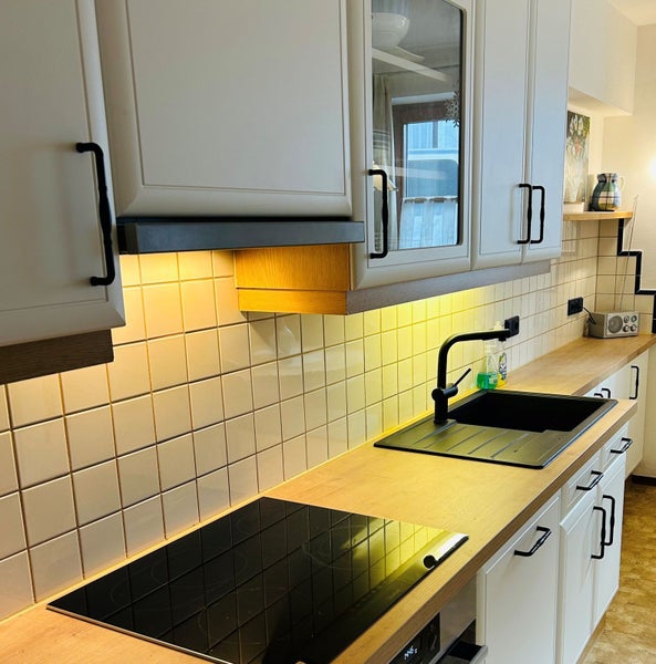 Küchenszene mit Küchenschränken, Spüle, Kochfeld und Fliesen