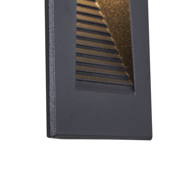 Detailansicht einer rechteckigen Wandeinbauleuchte aus Metall mit Lamellen zur Lichtlenkung und strukturierter Oberfläche.