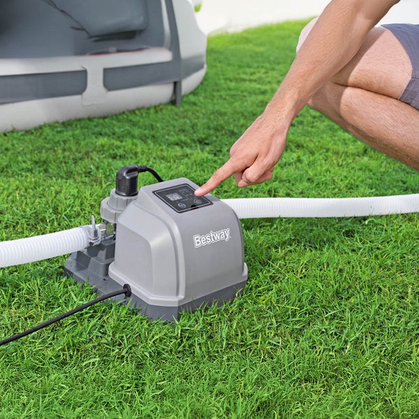 Bestway Logo auf einer Filterpumpe mit einem Rohr, die auf einer grünen Rasenfläche steht und von einer Person bedient wird.