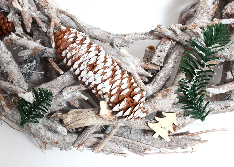 Dekorativer Adventskranz aus Ästen mit Tannenzapfen und Deko-Tannenbäumchen