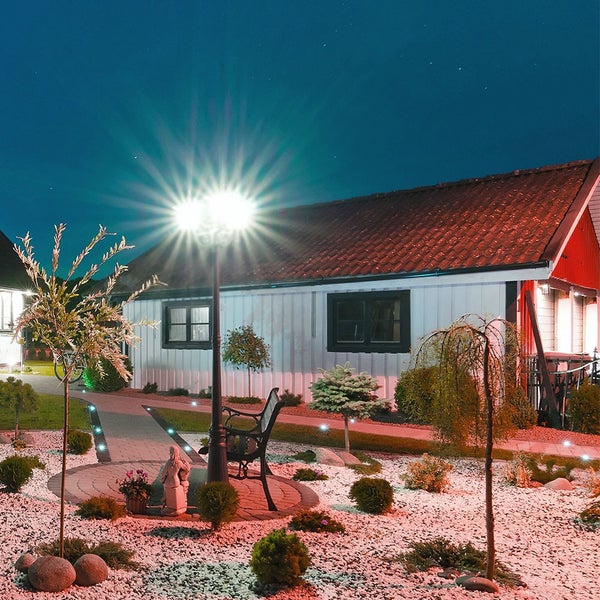 Gartenanlage mit Haus, Weg, Beleuchtung und Sitzbank bei Nacht