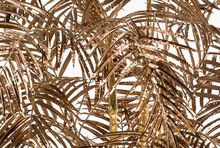 Nahaufnahme von goldfarbenen künstlichen Bambushalmen in einem schwarzen Kunststofftopf.