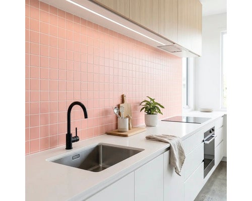 Moderne Küche mit Fliesenspiegel aus rosa quadratischen Mosaikfliesen, weißer Arbeitsplatte, schwarzer Armatur und Oberschränken aus hellem Holz.