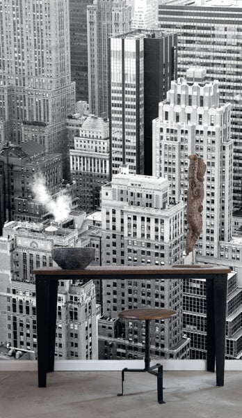 Fototapete mit einer urbanen Szene, die eine Stadtlandschaft mit Hochhäusern darstellt, ergänzt durch einen Tisch und einen Hocker