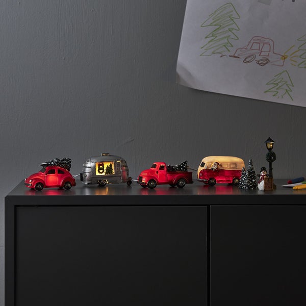 Dekorative Weihnachtsszene mit Oldtimern, Wohnwagen, Schneemann und Weihnachtsbaum auf einem Schrank
