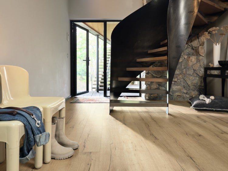 Ein moderner Eingangsbereich mit hellen Holzboden-Dielen, einer offenen Wendeltreppe aus Metall und Holz sowie Blick nach draußen durch eine Glastür.