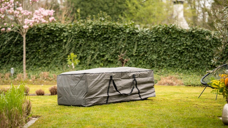 Graue Schutzhülle mit Tragegriffen auf Rasenfläche im Garten