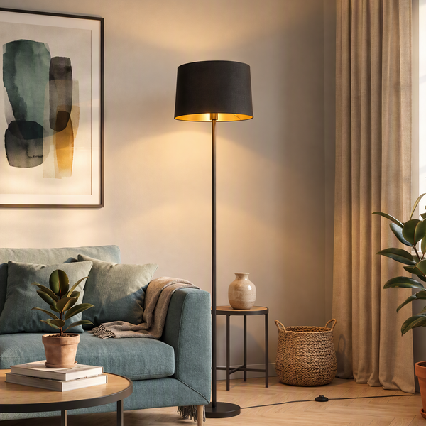 Moderne Stehleuchte mit zylindrischem Lampenschirm in einem gemütlichen Wohnzimmer mit Sofa, Beistelltisch und Pflanze.