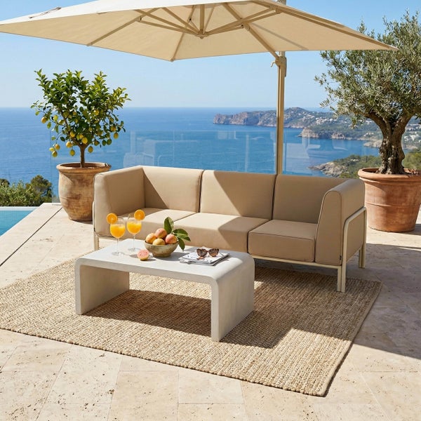 Moderne Gartenlounge auf einer Terrasse mit 3-Sitzer Sofa, Couchtisch, Sonnenschirm und Teppich mit Meerblick.