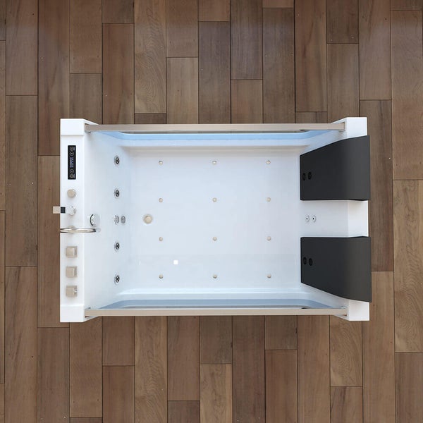 Rechteckige Whirlpool Badewanne mit Massagedüsen und zwei Kopfstützen in einer modernen Badezimmerumgebung mit Holzoptik Boden
