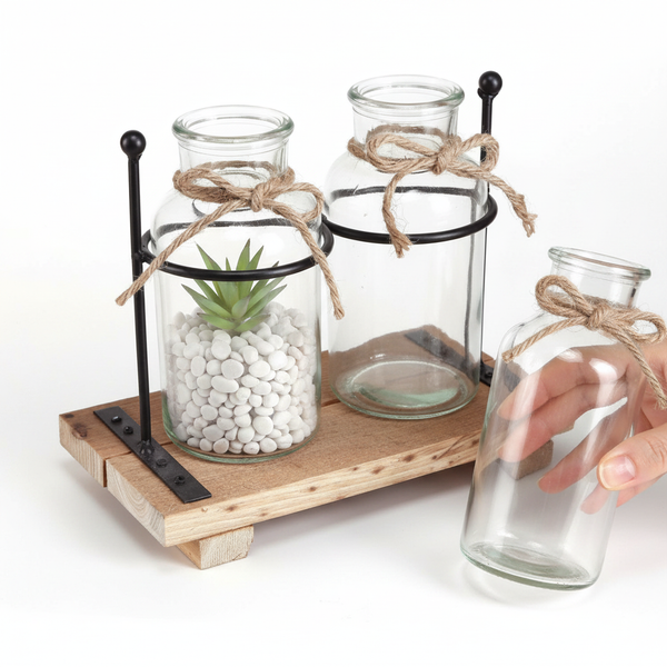 Dreiteiliges Glasvasen-Set auf einem Holztablett mit schwarzem Metallrahmen, inklusive künstlicher Sukkulente, Steinen und Juteschleifen.