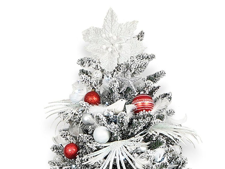 Festlich geschmückter, künstlicher Weihnachtsbaum mit Schneeoptik, dekoriert mit Weihnachtskugeln, Federn und einer großen Blüte als Spitze.
