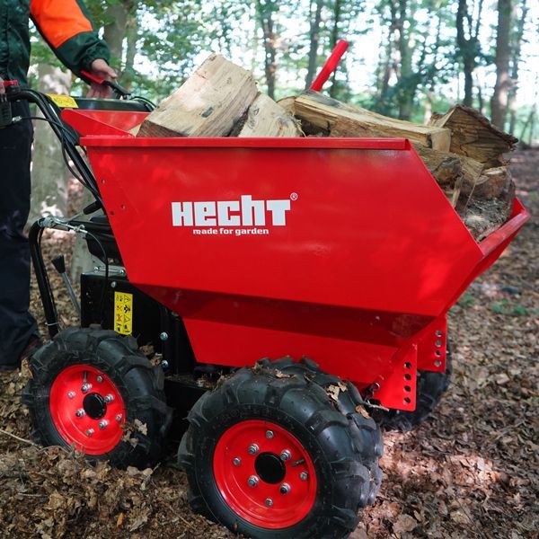 Hecht roter Motordumper beladen mit Brennholz in einem Wald. Minidumper mit grobstolligen Reifen und Allradantrieb für unwegsames Gelände.