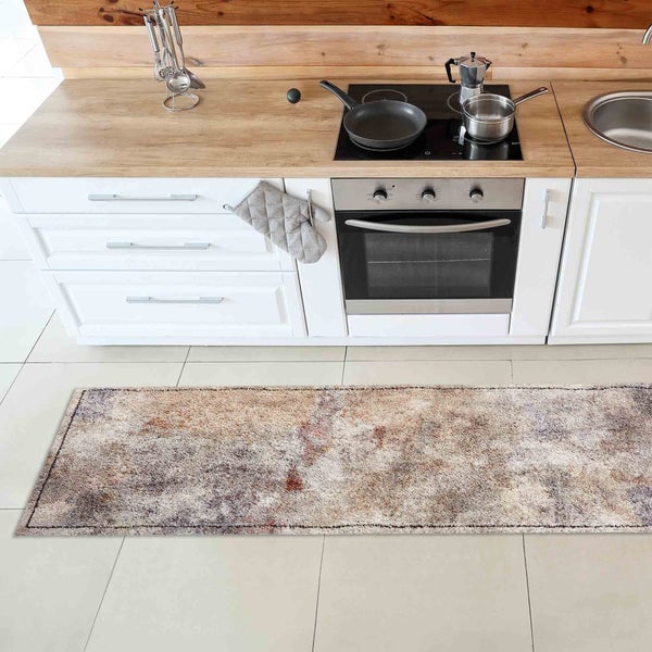 Küchenszene mit einem langflorigen Teppich vor weißen Küchenschränken.