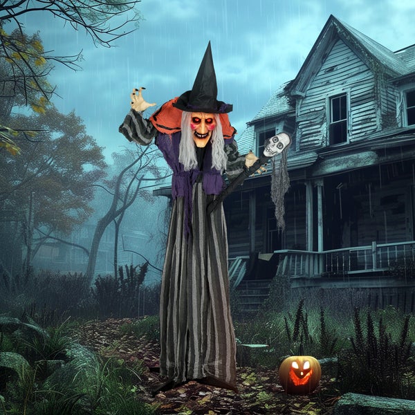 Halloween-Szene mit einer stehenden Hexen-Dekoration, Kürbis und einem gruseligen Haus im Hintergrund.