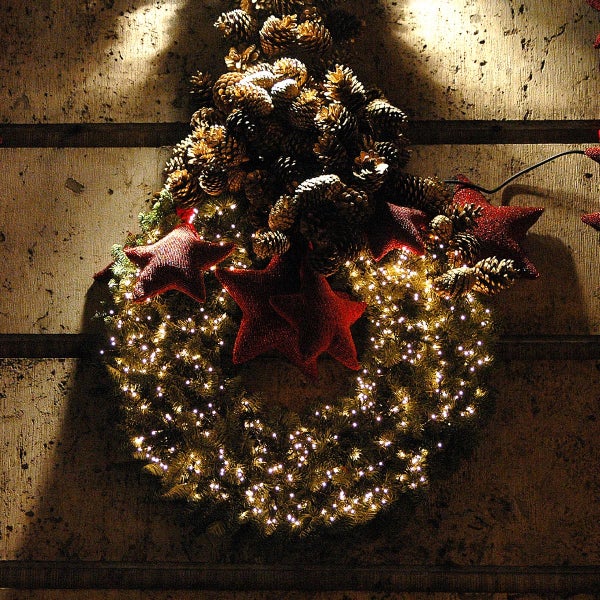 Beleuchteter Adventskranz mit Tannenzapfen und Sternen als Weihnachtsdekoration für die Wand.