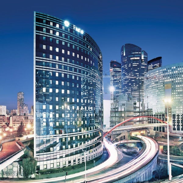 Stadtbild mit Bürogebäuden und Straßenverkehr bei Nacht