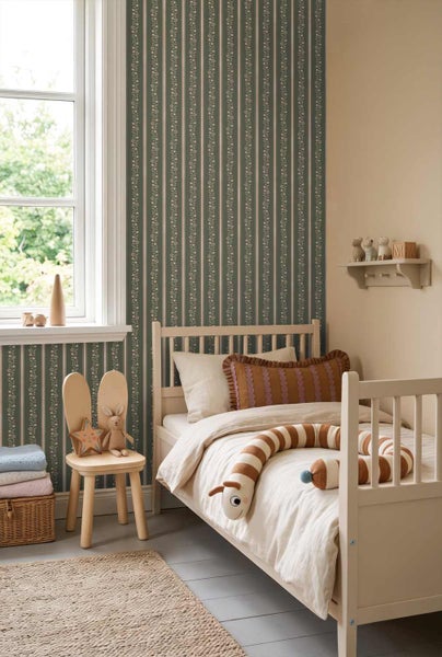 Helles Kinderzimmer mit Holzbett, Raupen-Kuscheltier und Tapete mit vertikalen Streifen und Blumenmustern.