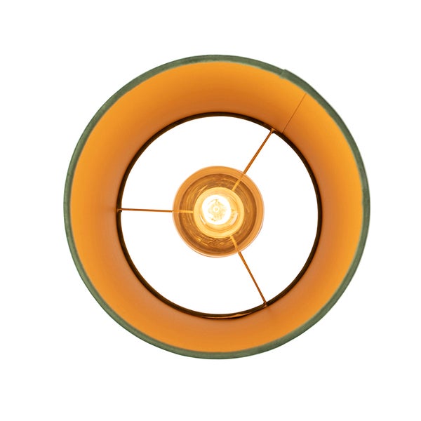 Draufsicht eines runden Lampenschirms mit grünem Textil und goldener Innenseite sowie eingeschaltetem Leuchtmittel.