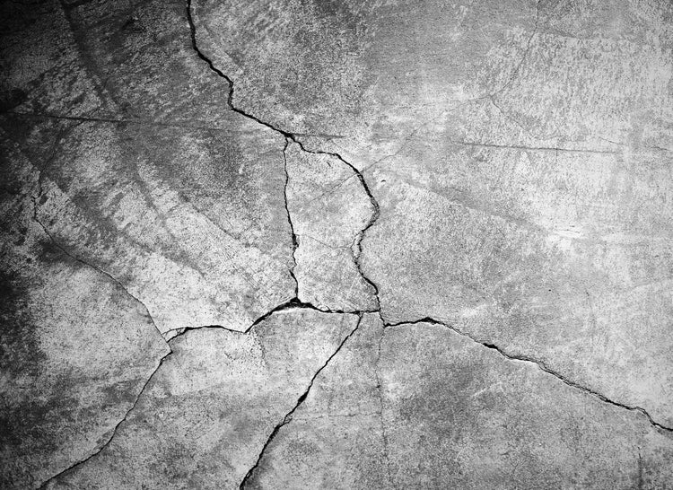 Rissiger Betonboden mit tiefen Spalten und rauer Oberflächenstruktur.