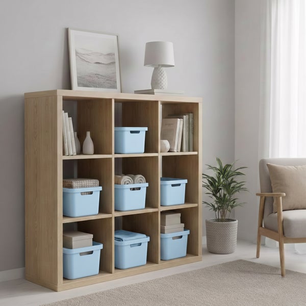 Helles Holzregal mit neun Fächern, dekoriert mit Aufbewahrungsboxen, Büchern, Vasen und einer Tischlampe in einem modern eingerichteten Raum.