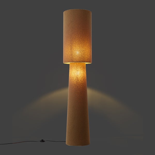 Stehleuchte mit zylindrischem Schirm und konischem Fuß in strukturierter Korkoptik, eingeschaltet mit warmem Licht.