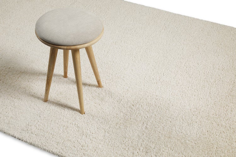 Hocker auf einem hellen, flauschigen Hochflor-Teppich mit weicher Struktur.