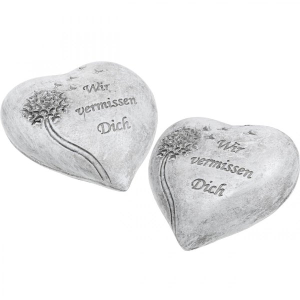 Zwei herzförmige Grabsteine mit der Aufschrift Wir vermissen Dich und einer Löwenzahn-Illustration.