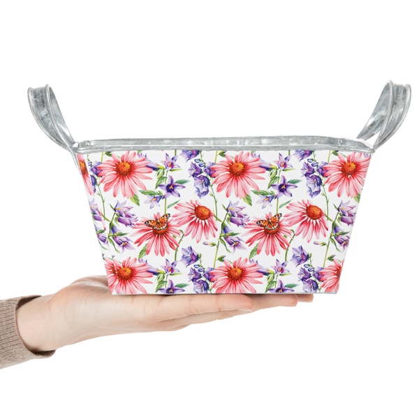 Kleine Metall-Pflanzwanne mit bunten Blumen, Schmetterlingen und zwei Griffen, in einer Hand gehalten.