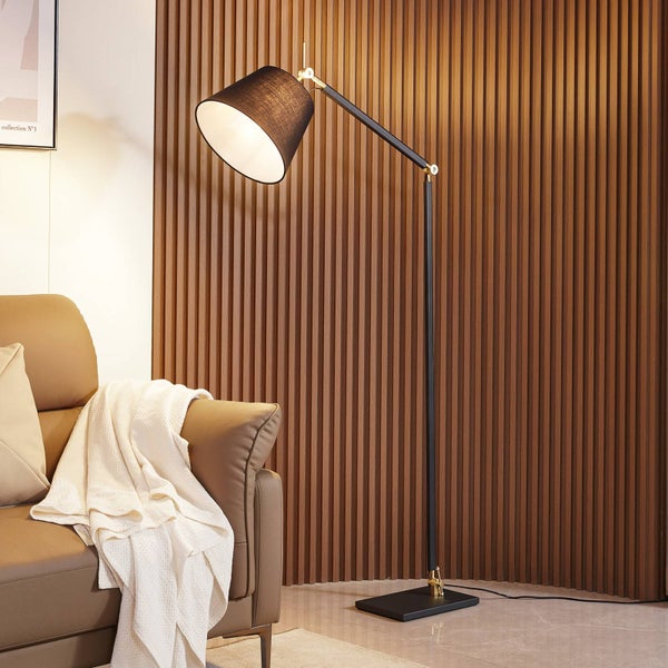 Stehleuchte mit schwarzem Lampenschirm und verstellbarem Arm neben einem Sofa