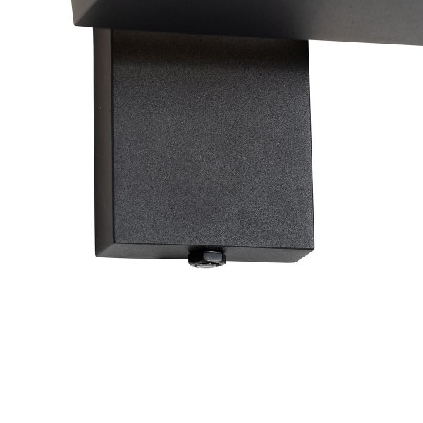 Detailaufnahme einer schwarzen rechteckigen Wandhalterung aus Metall mit strukturierter Oberfläche und Sechskantschraube an der Unterseite.