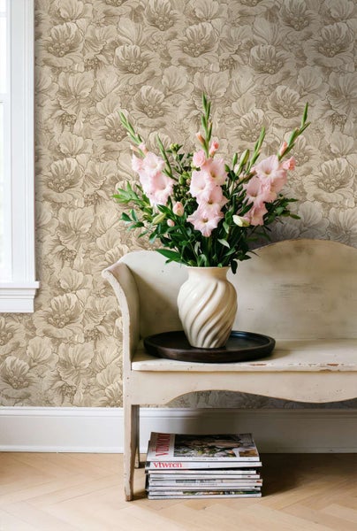 Wohnraum mit floraler Tapete, einer weißen Vintage Bank und einer Vase mit rosa Gladiolen vor einem Fenster.