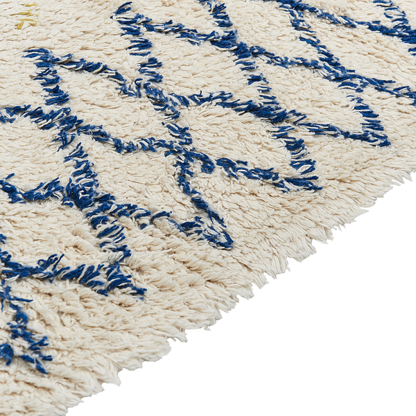 Nahaufnahme eines Hochflor-Teppichs mit blauem Rautenmuster.